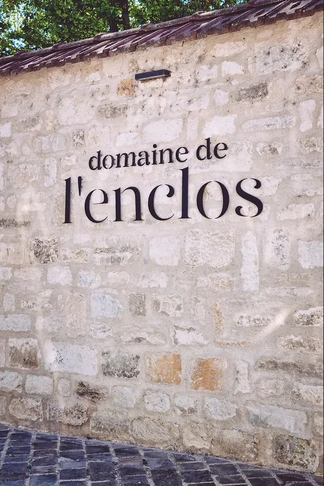 Stone wall with black lettering that reads domaine de l'enclos