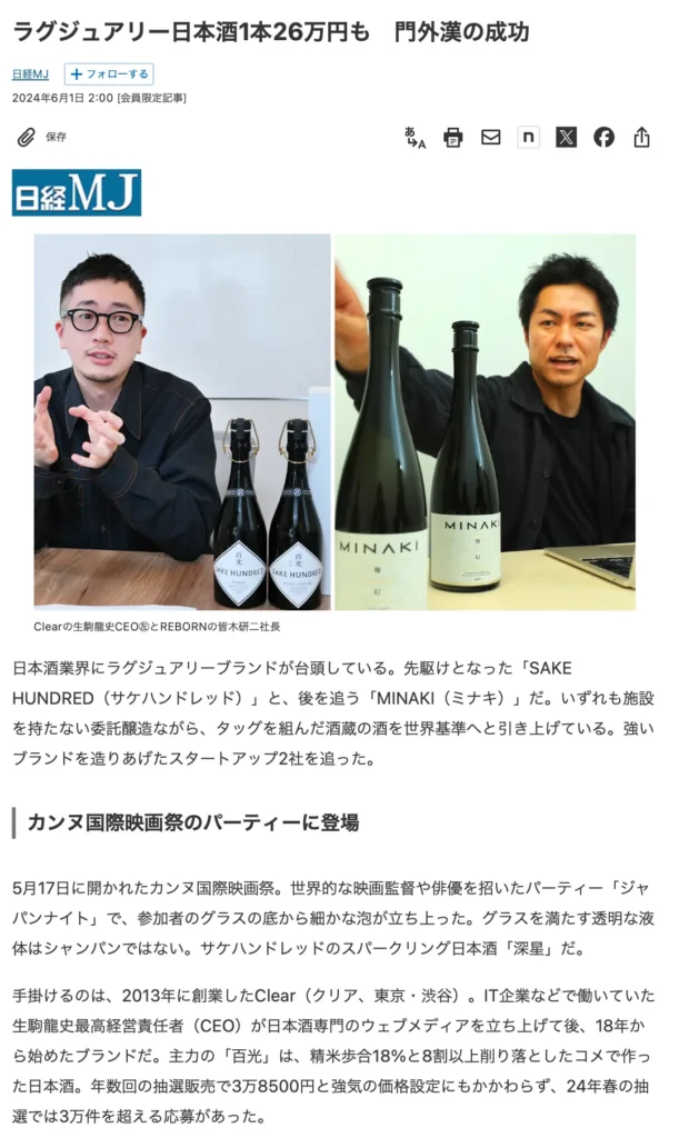 Two men sitting at a table with bottles of sake labeled SAKE HUNDRED and MINAKI