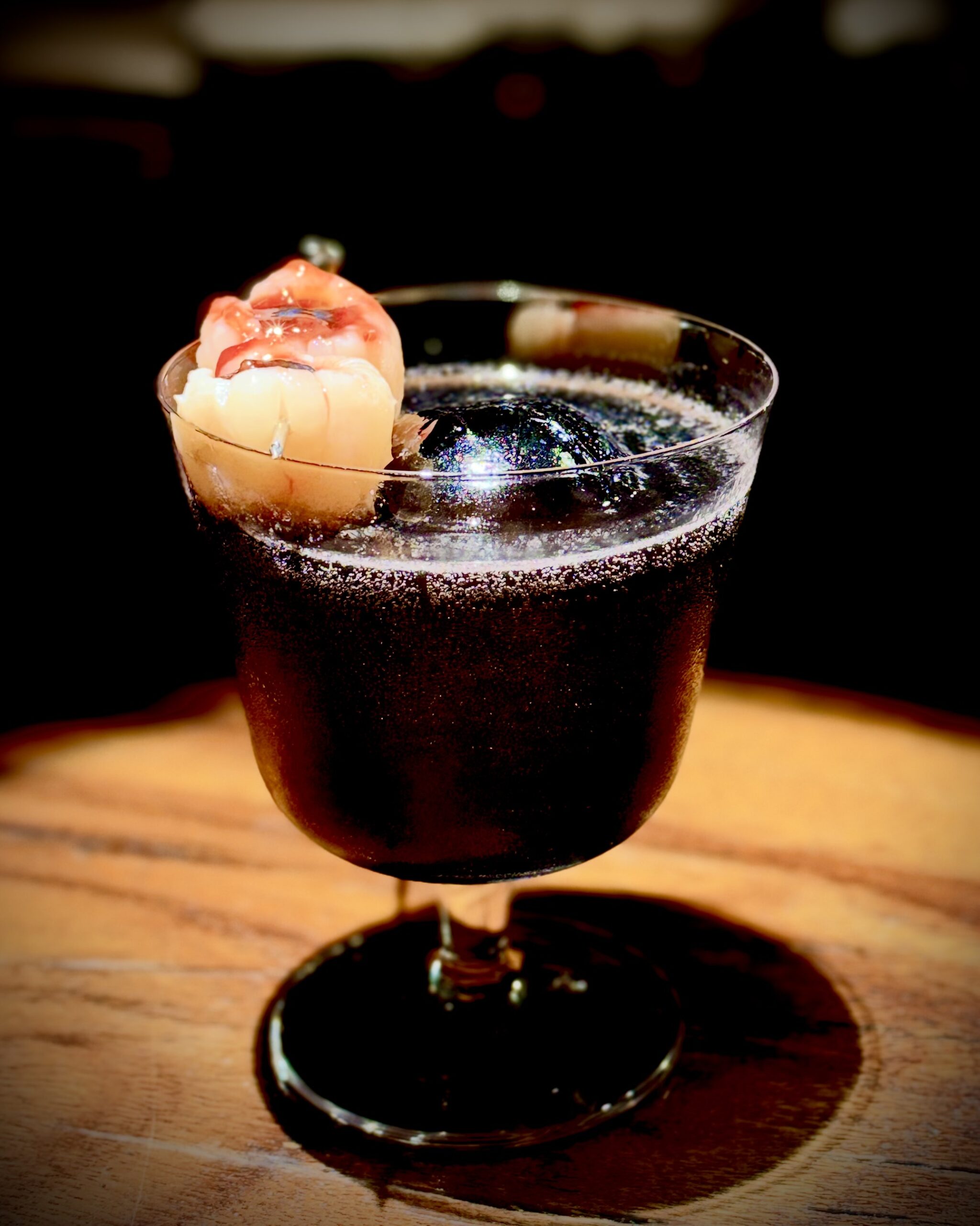 Fantome du Salon: a dark cocktail in a stemmed glass with a sculpted garnish